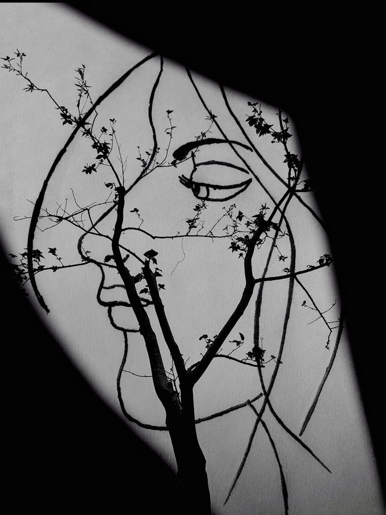 Black and white artistic image blending tree branches with a woman's face silhouette creating a unique composition.
